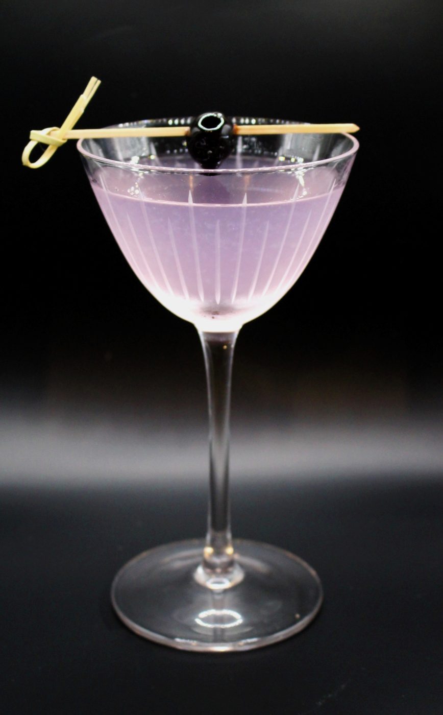 Signature cocktail in a coupe glass with a cherry garnish