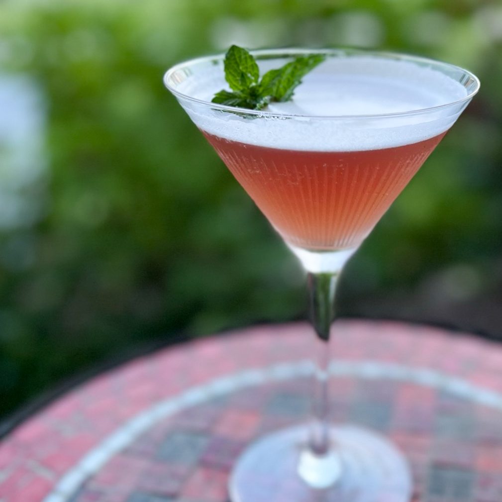Pink signature cocktail garnished with mint