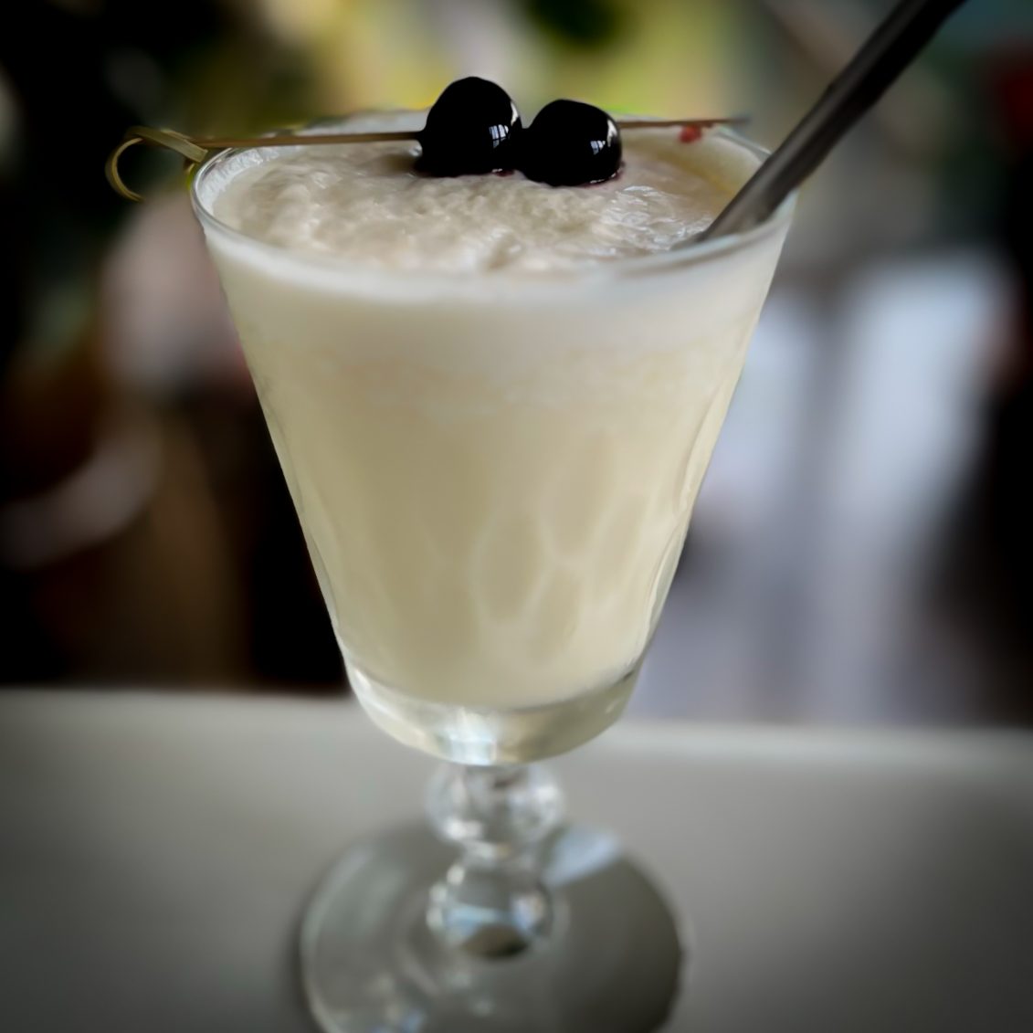 Frothy white cocktail garnished with berries