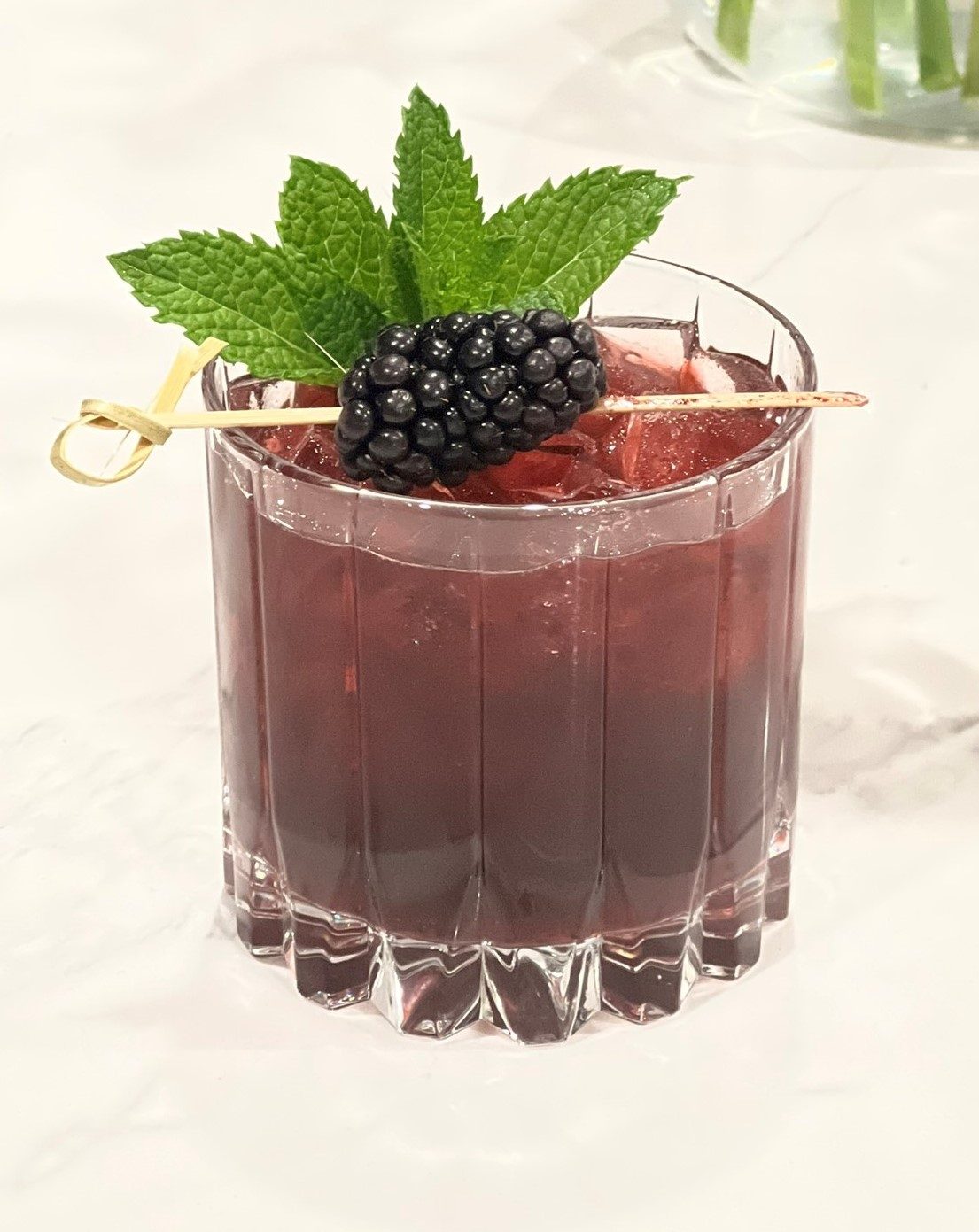 Dark berry cocktail garnished with a blackberry