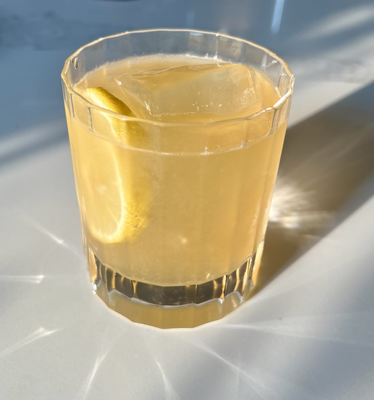 Craft cocktail with a lemon wheel in natural sunlight
